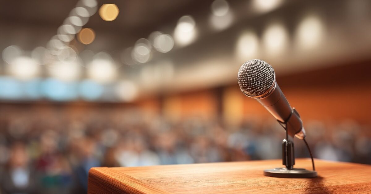 Microphone on a wooden podium facing a large audience, with a Melbourne marriage celebrant, MC a Life Event at a wedding.