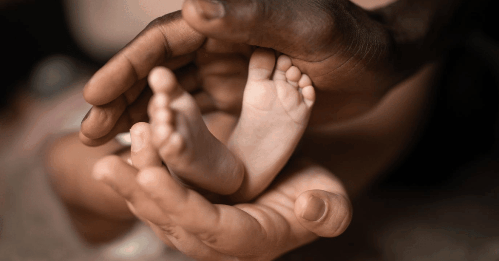 A close-up of a baby's feet in an adult's hands, representing the joy of new birth and the role of a birth celebrant.